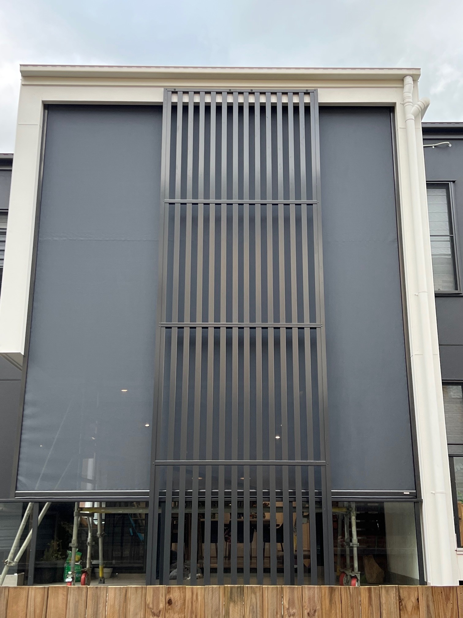 Double-storey motorised outdoor screens fitted alongside a vertical batten feature